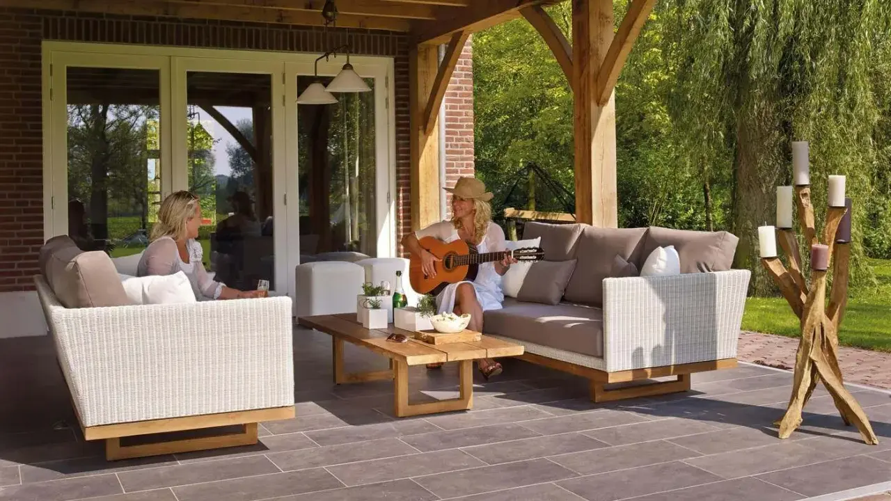 Kobieta gra na gitarze na tarasie, siedząc na sofie obok koleżanki. To idealne miejsce na relaks, jakby to był prywatny balkon.
