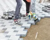 Układanie kostki brukowej na podsypce. Beton pod kostkę tworzy stabilne podłoże dla prac brukarskich.