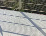 Nowy, biały balkon z żywicą, lśniący w słońcu. Cienie siatki tworzą ciekawy wzór na jego powierzchni.