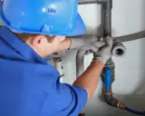 Instalator montuje odpowietrzenie kanału sanitarnego w domu parterowym.