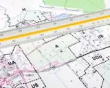 Plan zagospodarowania przestrzennego z naniesionymi strefami i podziałami. Linijka geodezyjna pomaga w precyzyjnym pomiarze.