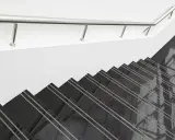 Nowoczesne schody z czarnego, polerowanego betonu na schody, z metalową poręczą.