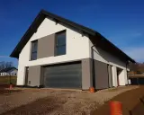 Nowoczesny dom w aurorach 19, z dwukolorową elewacją i garażem wbudowanym w bryłę.