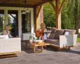 Kobieta gra na gitarze na tarasie, siedząc na sofie obok koleżanki. To idealne miejsce na relaks, jakby to był prywatny balkon.