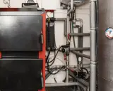 Kotłownia z piecem i skomplikowaną instalacją hydrauliczną. Widoczna wentylacja w kotłowni zapewnia prawidłowe działanie systemu.