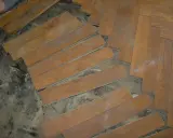Drewniana podłoga w jodełkę, częściowo rozebrana. Widać pojedyncze deseczki i fragmenty ułożenia. Czy to subit?