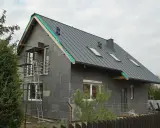 Przebudowa starego domu projekty: szary dom w trakcie budowy, z nowym dachem, oknami i rusztowaniami.