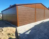 Nowoczesny projekt garażu z wiatą, wykonany z brązowej blachy imitującej drewno. Idealne rozwiązanie dla Twojego podwórka.