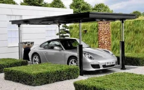 Srebrne Porsche pod nowoczesną wiatą, która może być częścią domu z garażem podziemnym.