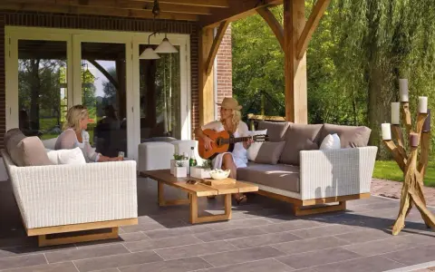 Kobieta gra na gitarze na tarasie, siedząc na sofie obok koleżanki. To idealne miejsce na relaks, jakby to był prywatny balkon.