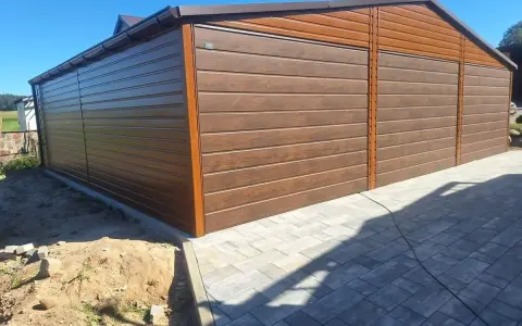 Nowoczesny projekt garażu z wiatą, wykonany z brązowej blachy imitującej drewno. Idealne rozwiązanie dla Twojego podwórka.