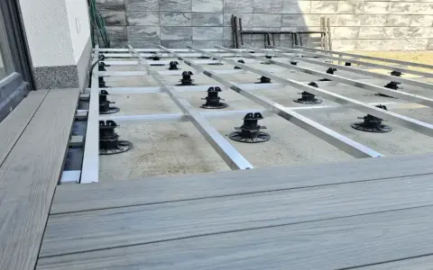 Budowa tarasu z deski kompozytowej. Widoczna konstrukcja nośna z aluminiowych profili i regulowanych podpór.