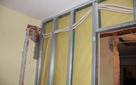 Trwa wymiana instalacji elektrycznej w mieszkaniu. Widać metalowy stelaż, żółtą membranę i nowe przewody elektryczne w peszlach.