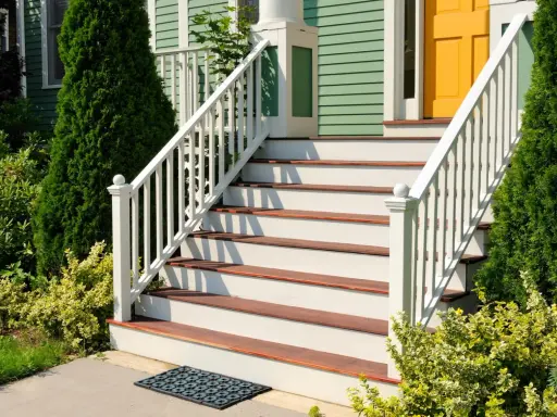 Eleganckie schody zewnętrzne z białymi balustradami i drewnianymi stopniami. Inspiracje na schody zewnętrzne, które dodadzą uroku każdemu domowi.