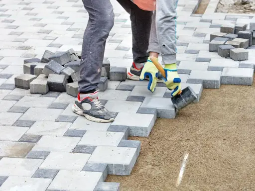 Układanie kostki brukowej na podsypce. Beton pod kostkę tworzy stabilne podłoże dla prac brukarskich.