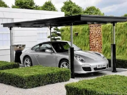 Srebrne Porsche pod nowoczesną wiatą, która może być częścią domu z garażem podziemnym.