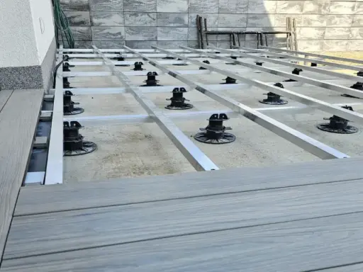 Budowa tarasu z deski kompozytowej. Widoczna konstrukcja nośna z aluminiowych profili i regulowanych podpór.