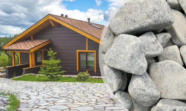 Elegancki podjazd z kamienia prowadzi do przytulnego drewnianego domu. Obok widać stos dużych, szarych kamieni, idealnych do stworzenia podobnej nawierzchni.