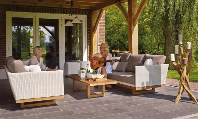 Kobieta gra na gitarze na tarasie, siedząc na sofie obok koleżanki. To idealne miejsce na relaks, jakby to był prywatny balkon.