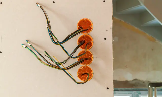 Instalacja elektryczna w domu drewnianym schemat: przewody wychodzące z puszek instalacyjnych w ścianie z płyt gipsowo-kartonowych.