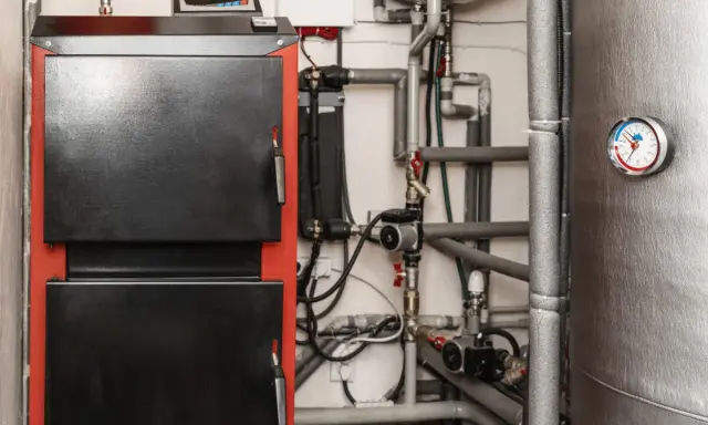 Kotłownia z piecem i skomplikowaną instalacją hydrauliczną. Widoczna wentylacja w kotłowni zapewnia prawidłowe działanie systemu.