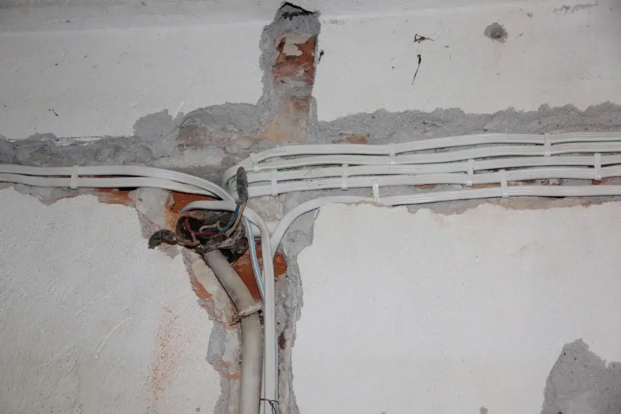 Nowe kable elektryczne w trakcie wymiany instalacji elektrycznej w mieszkaniu. Widoczna puszka rozdzielcza i świeżo położone przewody.
